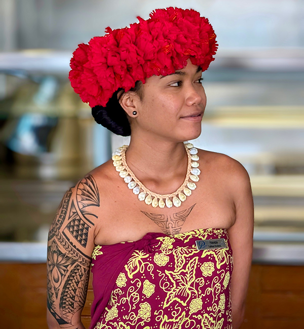 Einheimische und Mitarbeiterin auf der MS Paul Gauguin. Sie hat viele traditionelle Tattoos und eine Blumenkrone und Muschelkette an